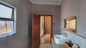 A bathroom with a sink, mirror, and window.