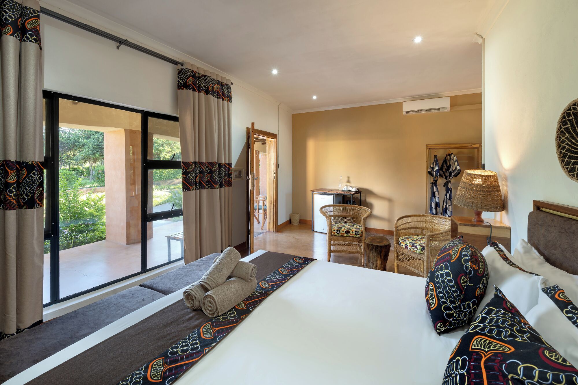 Habitación de hotel con cama, escritorio, silla, lámpara y vista al exterior.