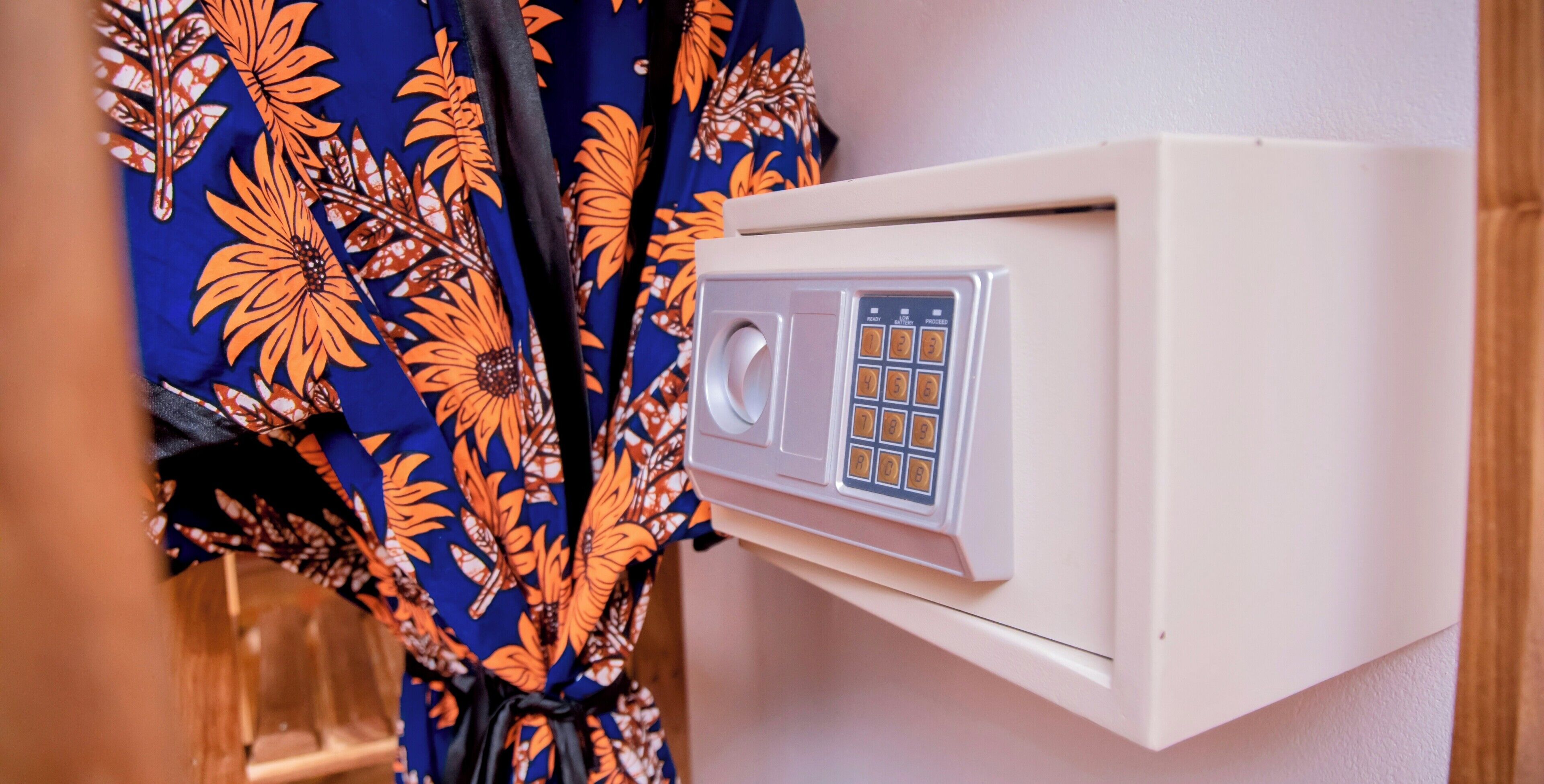 A wall-mounted thermostat with a numerical keypad, located in a room with a patterned fabric draped over a wooden structure.