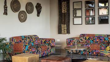 A room with a high ceiling, a ceiling fan, patterned sofas, a coffee table, and wall decor.