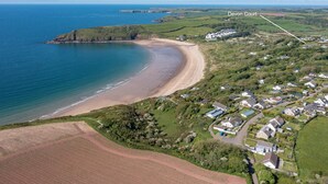 Vista aérea de Devon Court, mostrando uma praia costeira, casas residenciais e campos agrícolas.