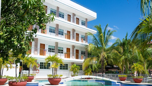Ein Hotel mit Pool, umgeben von Palmen und Topfpflanzen.