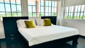 Ein modernes Hotelzimmer mit einem großen Bett, Blick auf Grünflächen und einem Fliesenboden.