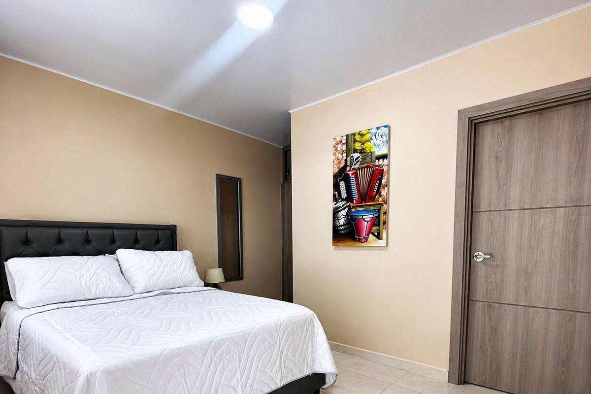 Une chambre à coucher avec un lit, une porte et une œuvre d’art accrochée au mur.