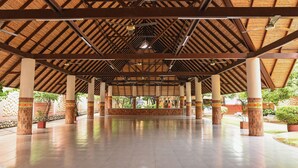 Eine offene Pagode mit hoher Decke, gestützt von Säulen mit verzierten Basen, und einem gefliesten Boden.