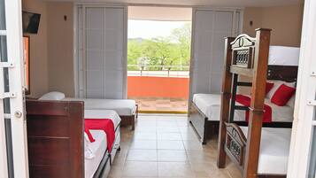 Habitación de hotel con dos camas individuales, una litera de madera y un balcón con vistas a zonas verdes.