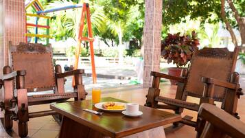 Una mesa de madera con un plato de comida, una taza y un vaso de jugo de naranja.