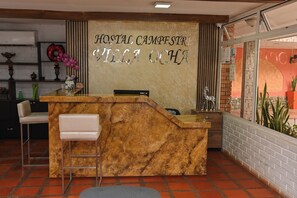 Een receptiebalie met een bord waarop 'HOSTAL CAMPESTRE VILLA DE CHICA' staat.