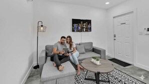 Una sala de estar moderna con un sofá gris, una mesa de centro, una lámpara de pie y una pintura de un paisaje urbano en la pared.