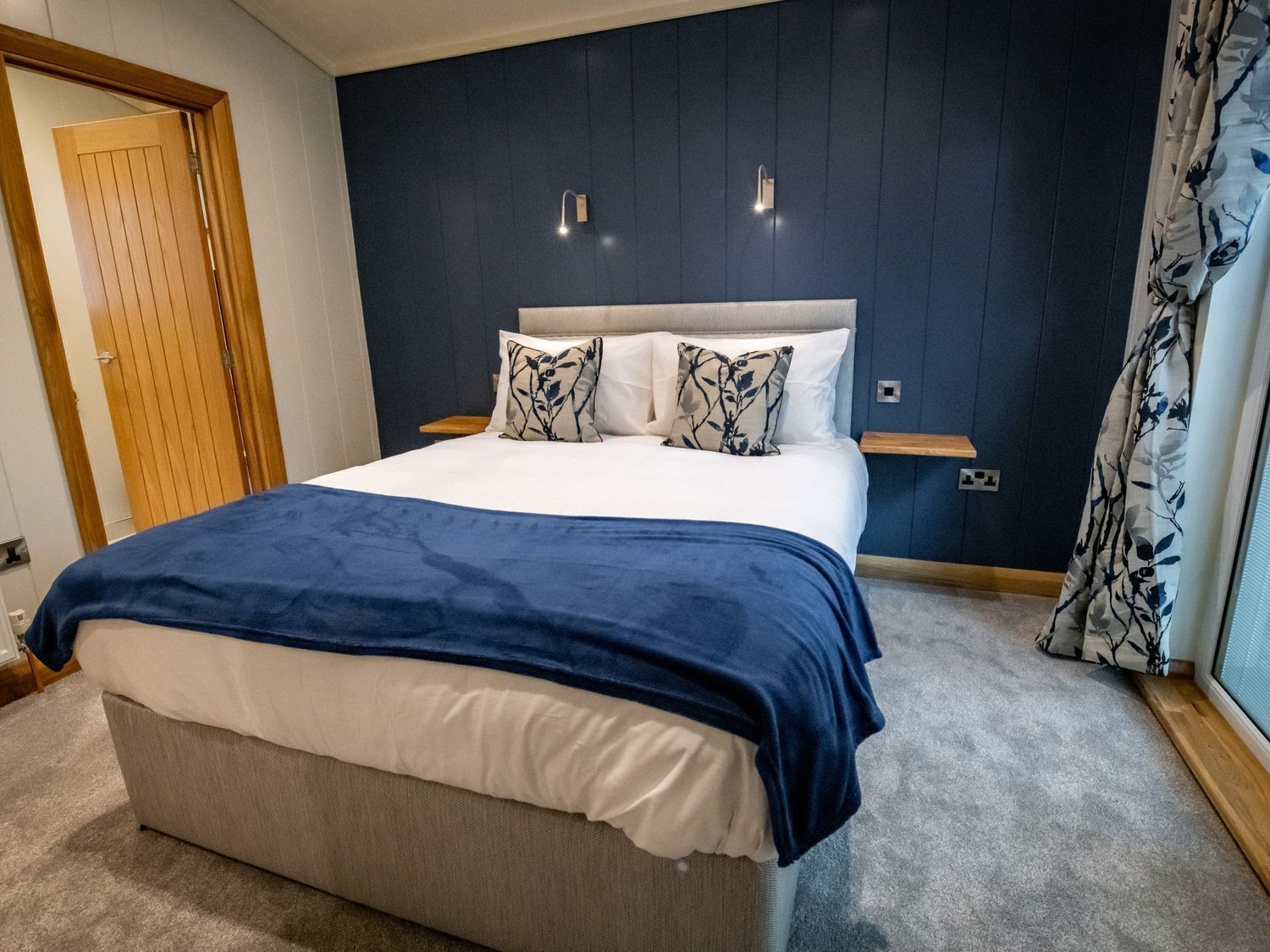 Ein Schlafzimmer mit einem Bett, einem Nachttisch, einer Wandleuchte und einer Tür.