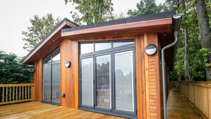 Une cabane moderne en bois, dotée de grandes portes-fenêtres coulissantes et d’une terrasse en bois.