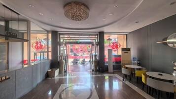 Un hall de hotel con mostrador de recepción, zona de estar y una araña.