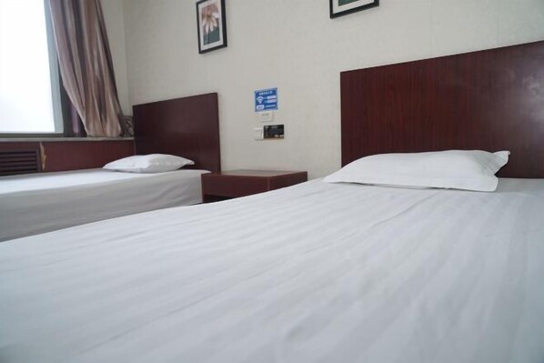 A hotel room with two single beds, a wooden headboard, a nightstand, and a window with curtains. - Xiangzheng Hotel (Qi County)