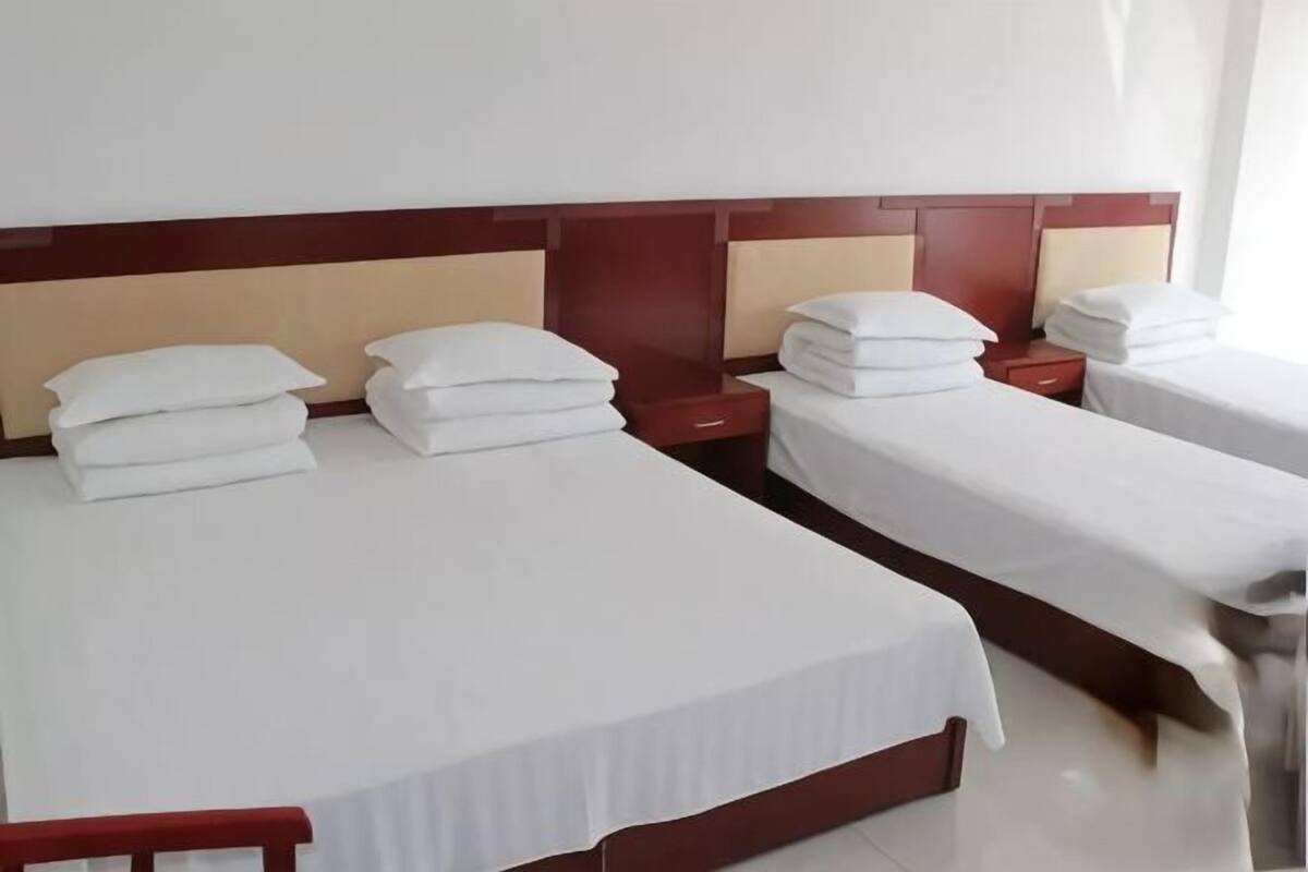 Ein Hotelzimmer mit zwei Betten, jeweils mit weißen Bettwäsche und Kissen, Holz-Kopfteilen und Nachttischen.