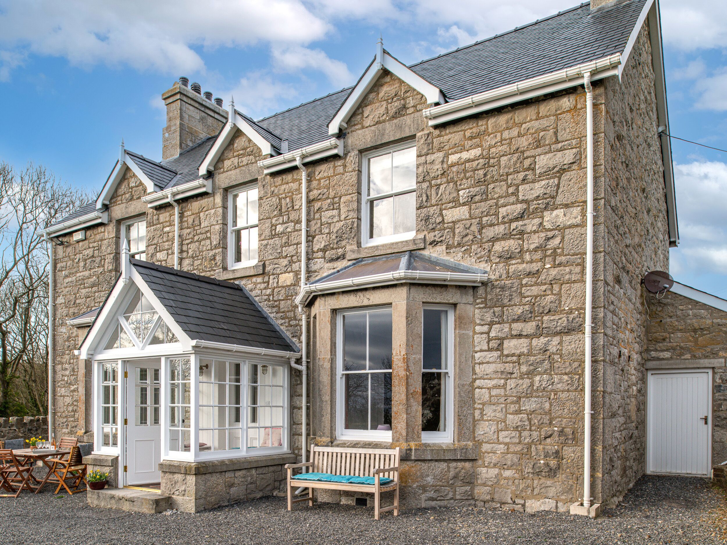 A stone building with a large window, a bench, and a door.