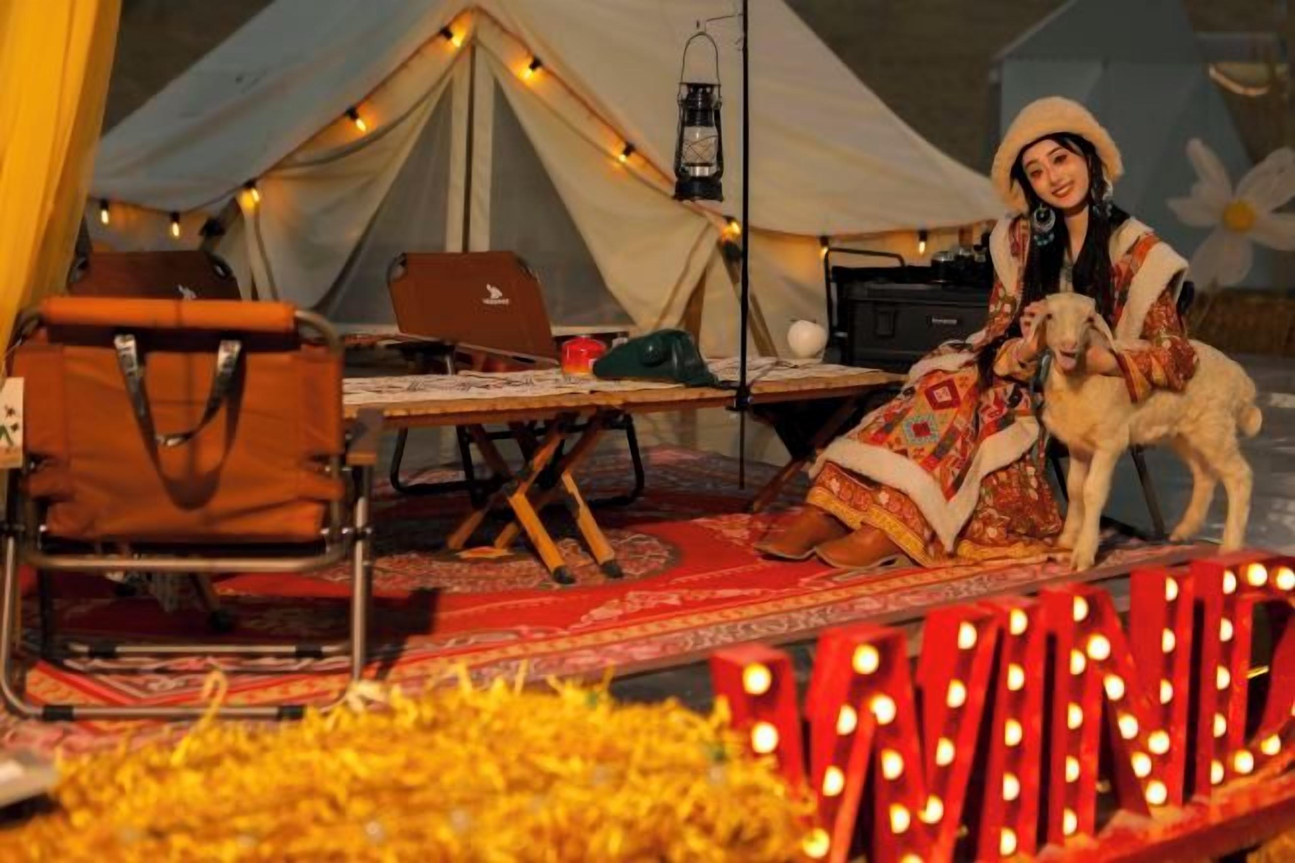 A tent with a laptop, a chair, and a table with a blanket.