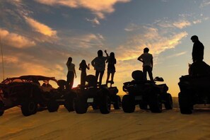 Un grupo de personas en cuatrimotos al atardecer.