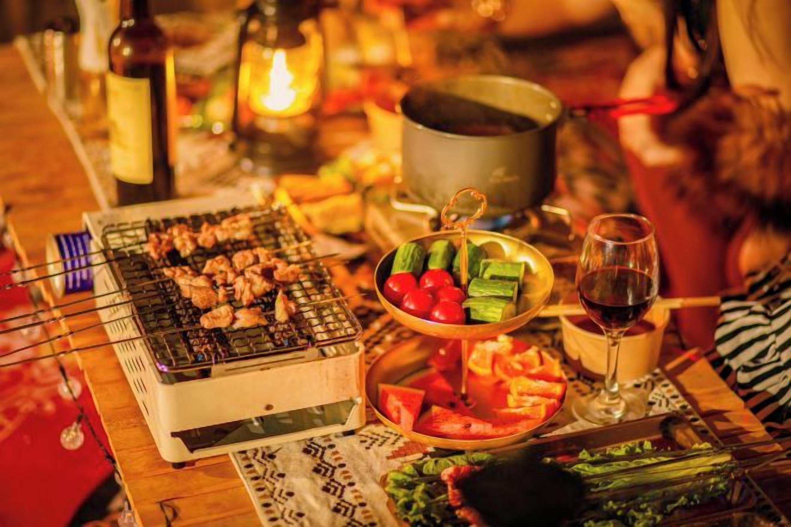 Une table avec un gril, des légumes et un verre à vin.