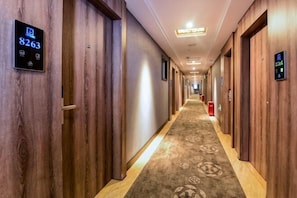 Un pasillo de hotel con paredes de madera, pisos alfombrados y puertas numeradas.