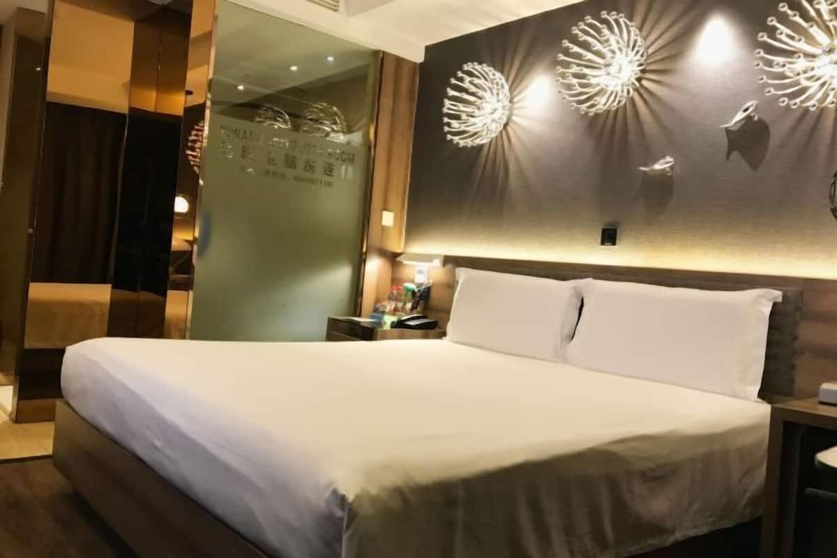 Ein Hotelzimmer mit einem großen Bett, einem Nachttisch und einer Wand mit dekorativer Beleuchtung.