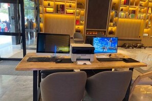 A hotel lobby with a reception desk, two computer monitors, and a printer.