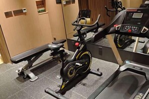 A stationary bike and a treadmill in a gym area with a mirror reflecting the equipment.