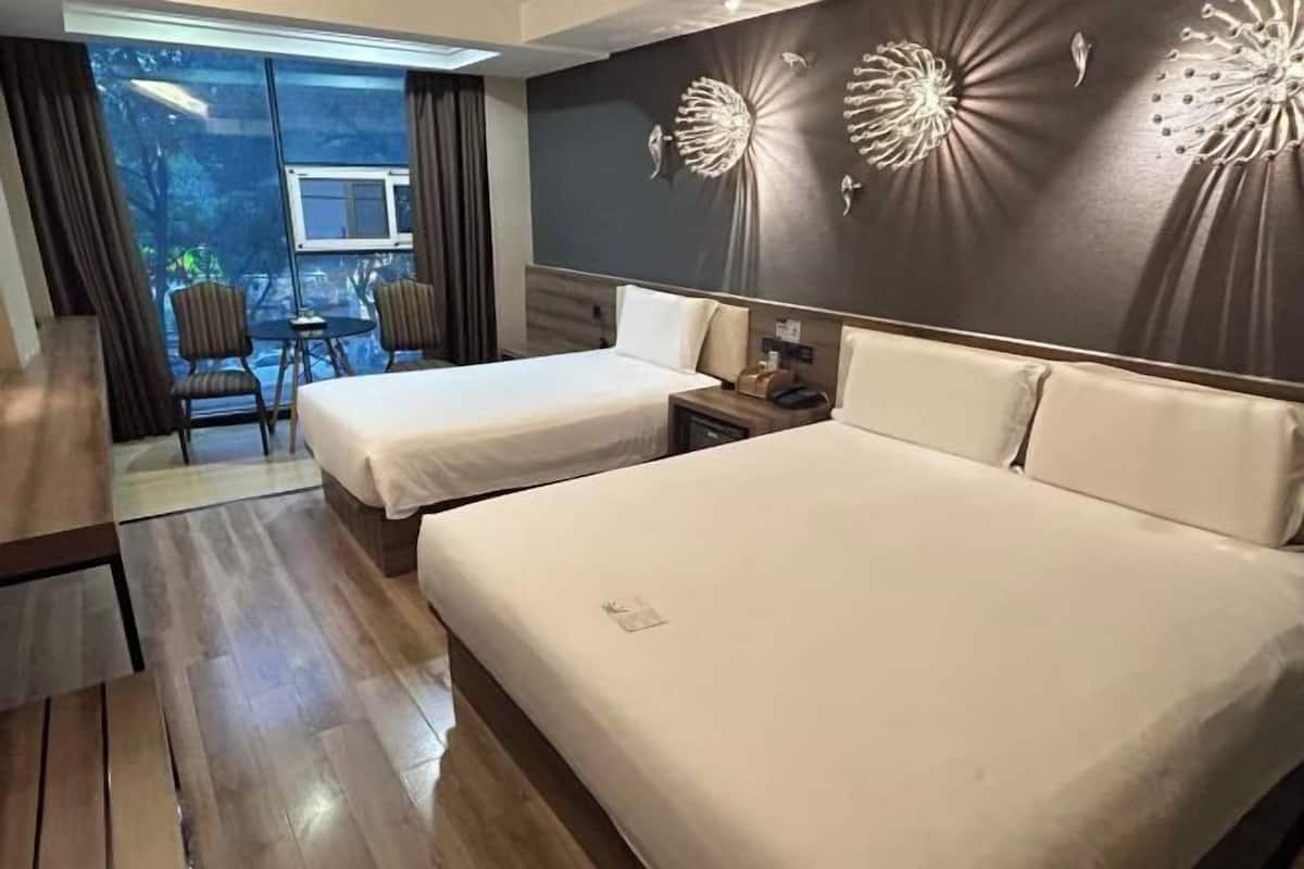 Ein Hotelzimmer mit zwei Betten, einem kleinen Tisch, Stühlen und einer Wandverzierung.