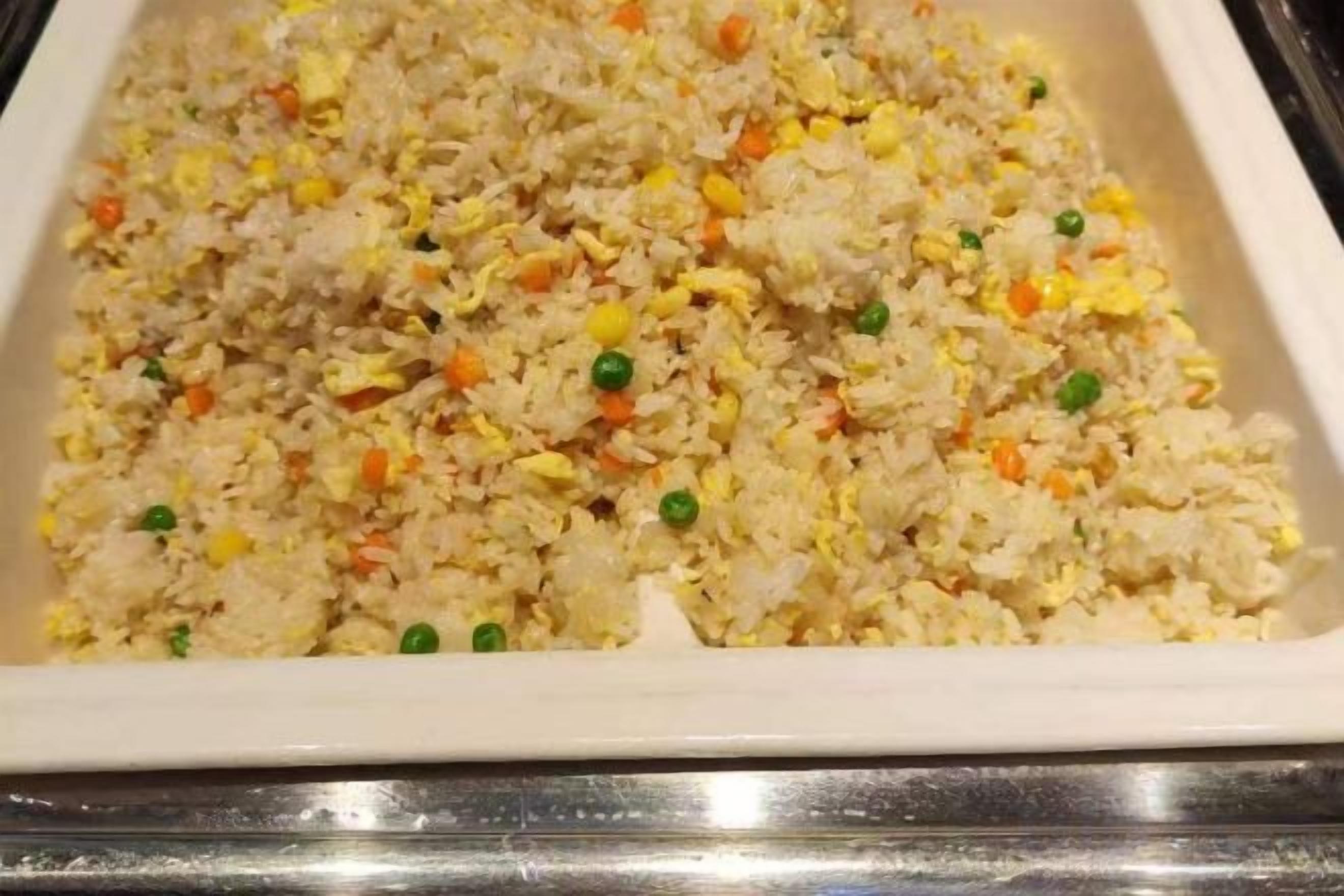A tray of fried rice with vegetables.