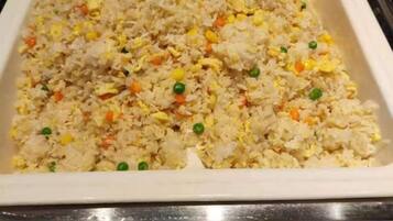 A tray of fried rice with vegetables.