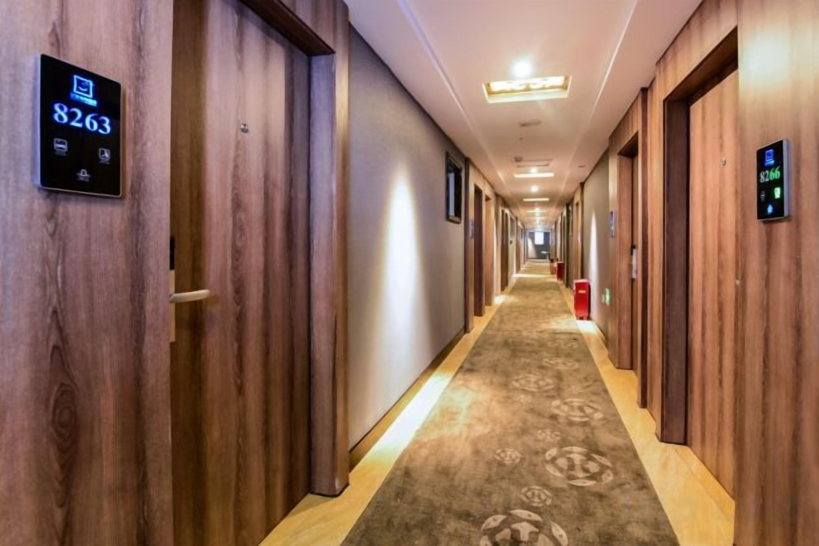 Un pasillo de hotel con paredes de madera, puertas numeradas y suelo alfombrado.