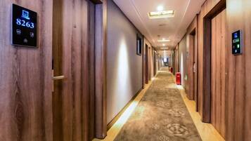 Un pasillo de hotel con paredes de madera, puertas numeradas y suelo alfombrado.