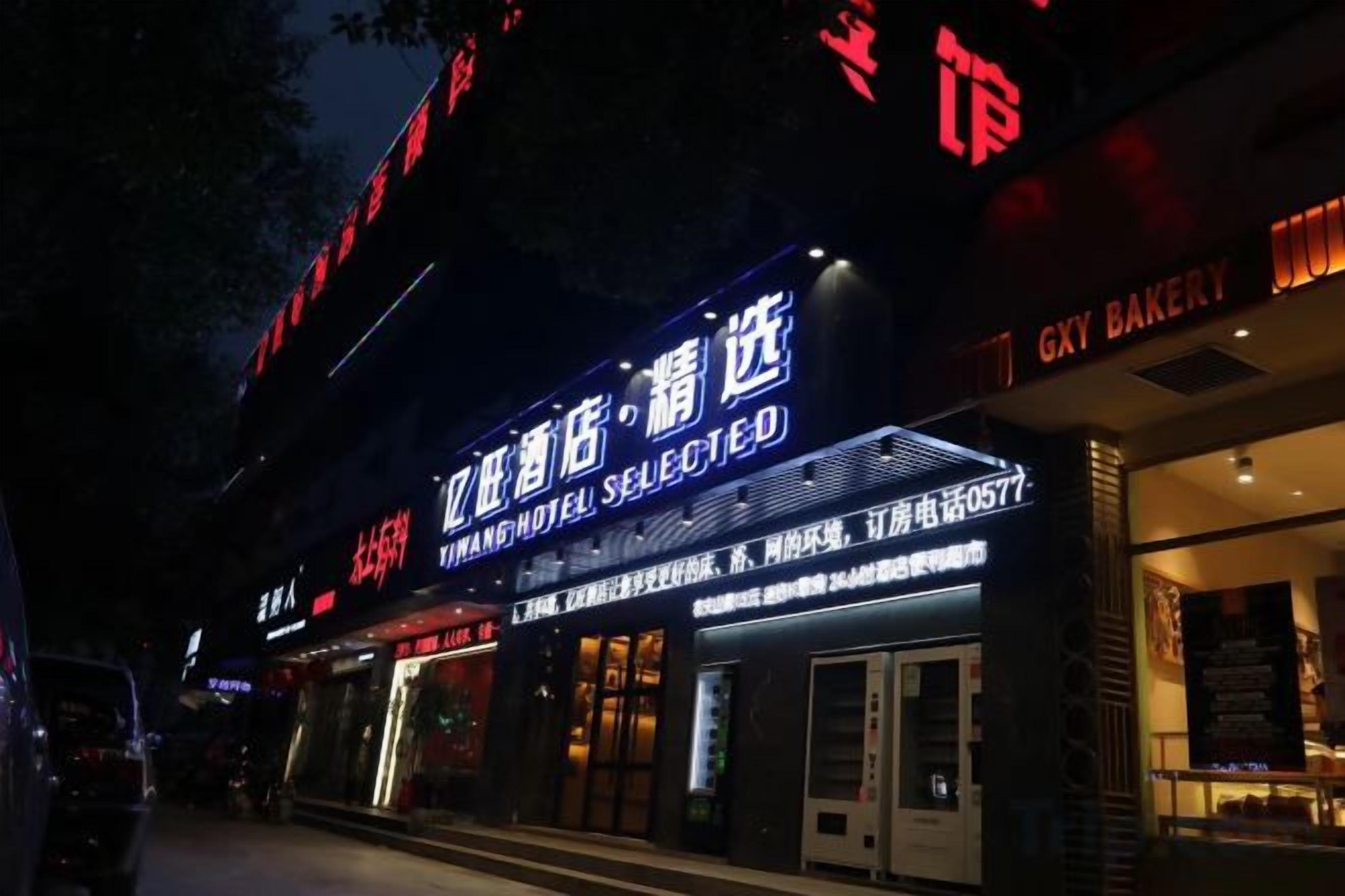 A hotel exterior with illuminated signage, a storefront, and a visible entrance.