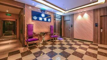 A hotel lobby with a checkered floor, a reception desk, and purple seating.