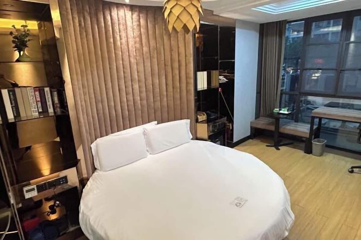 Ein Hotelzimmer mit einem großen Bett, einem Kleiderschrank, einem Schreibtisch und einem Fenster mit Stadtblick.