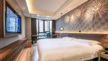 A modern hotel room with a large bed, a desk, and a TV mounted on the wall.