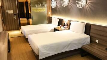 A hotel room with two beds, a wooden floor, a desk with a lamp, and a wall with decorative elements.