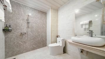 A modern bathroom with a marble shower, a white toilet, and a large sink with a mirror.