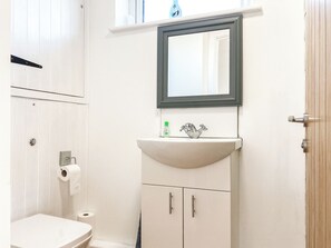 A bathroom with a white toilet, a sink with a mirror above it, and a door to the right.
