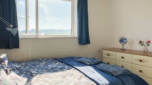 A bedroom with a bed, a dresser, a mirror, and a window with curtains.