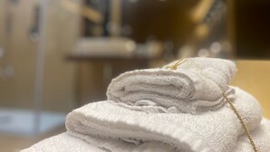A stack of white towels with a gold string tied around them, placed on a surface in a room with a blurred background. - SUITES IN THE HEART OF NAPLES WITHIN WALKING DISTANCE OF MAJOR ATTRACTIONS (Napoli)