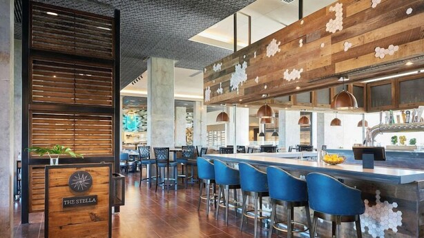 Un espace bar moderne agrémenté d’éléments en bois, de tabourets de bar bleus et d’un comptoir central.