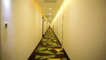 A long, narrow hallway with a patterned floor and doors on both sides leading to rooms.