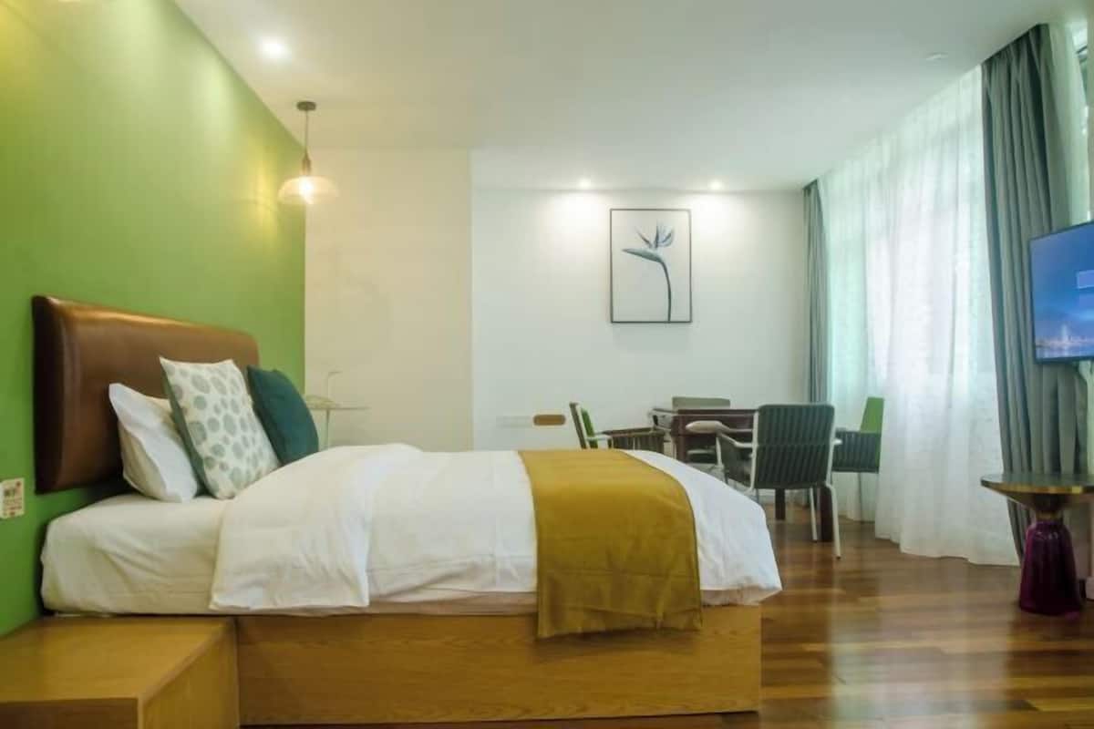 A hotel room with a bed, a desk, a chair, a TV, and a painting on the wall.