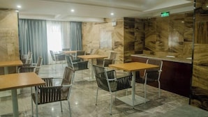 A modern dining area with marble walls, wooden tables, and metal chairs. - Yabo Hotel (Hengyang)