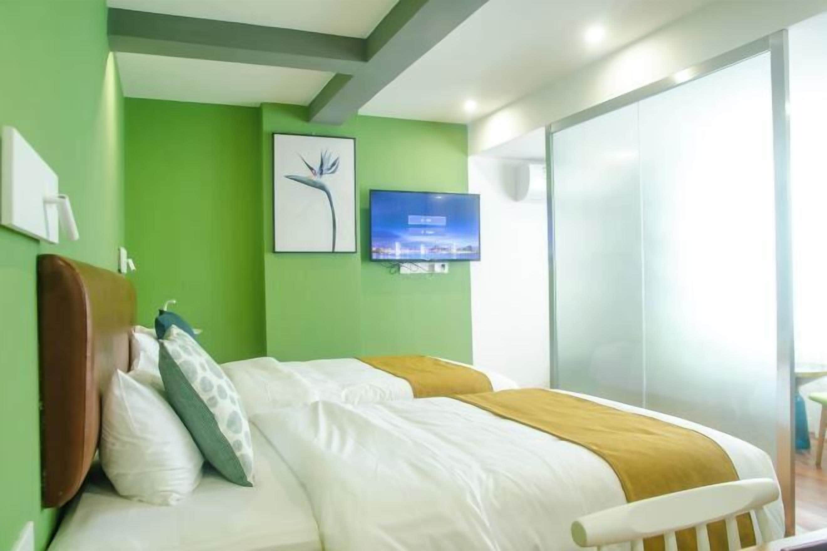 A hotel room with a bed, a television, a picture on the wall, and a window.