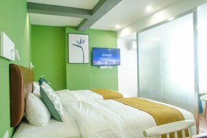 Una habitación de hotel con una cama, televisión, un cuadro en la pared y una ventana.