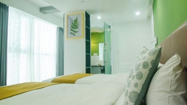A hotel room with a bed, a window with curtains, a green wall, and a framed picture on the wall. - Yabo Hotel (Hengyang)