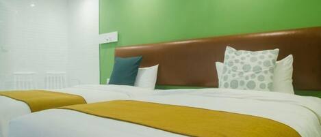 A hotel room with two beds, green walls, white bedding, and a brown headboard.