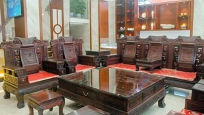 A traditional wooden furniture set with a glass-top coffee table, red cushions, and a wooden cabinet with shelves. - Yabo Hotel (Hengyang)