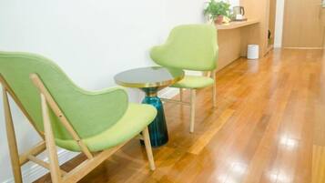 A room with two green chairs, a small round table, and a wooden floor.